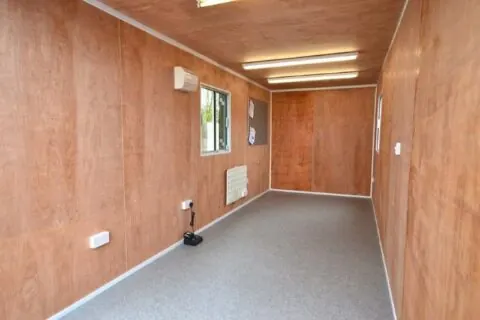Phòng bên trong container có vách gỗ và sàn chống trơn, bố trí khu thay đồ cho công nhân