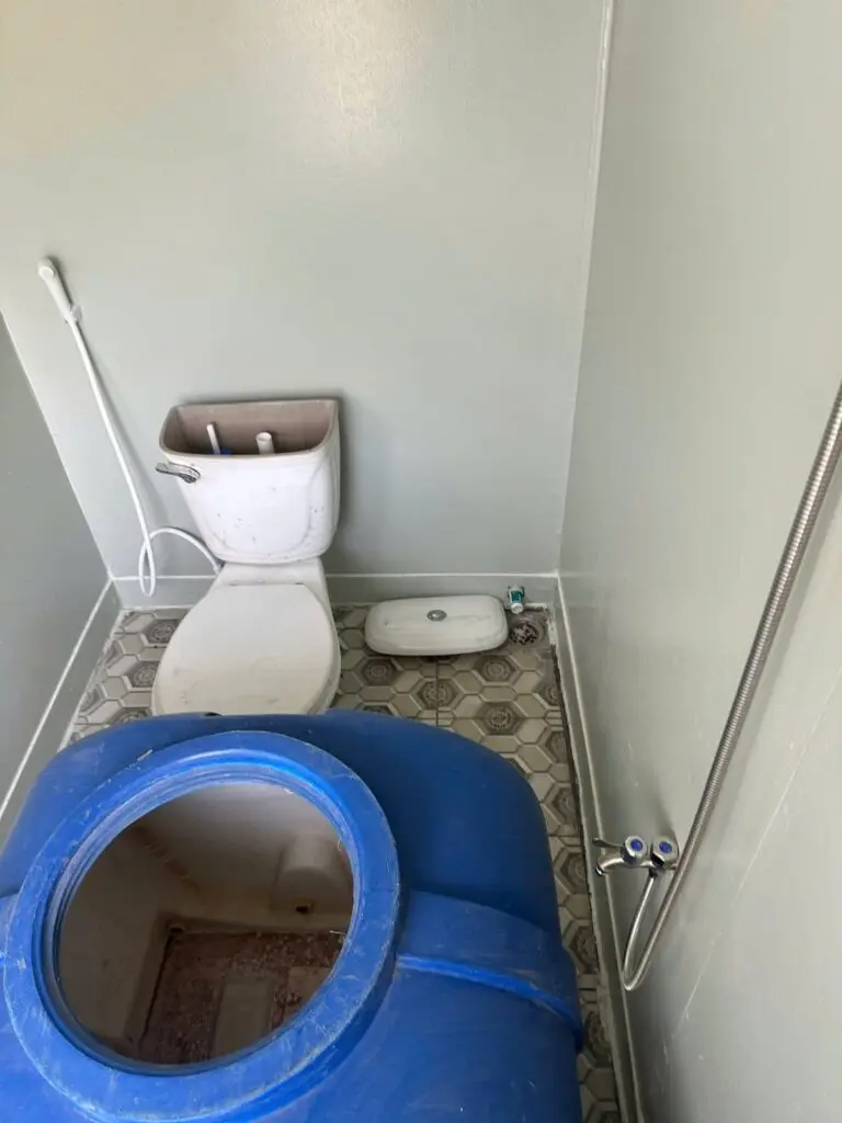Bên trong container vệ sinh 10ft có bồn cầu, bồn nước xanh và tay vịn tại Củ Chi