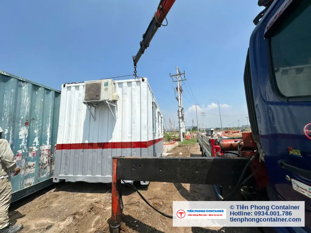Cẩu hạ container văn phòng 20ft trắng sọc đỏ có máy lạnh, cạnh container xanh ngọc đã đặt tại Aqua City