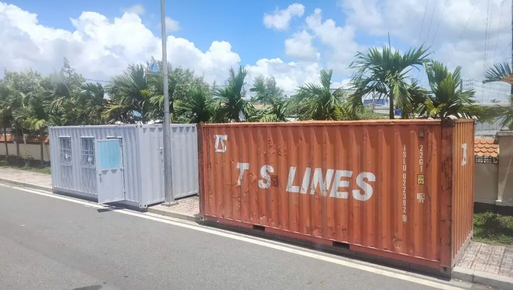 Container văn phòng 20ft sơn xám đặt cạnh container kho 20ft màu cam trên đường vào KCN Vĩnh Lộc