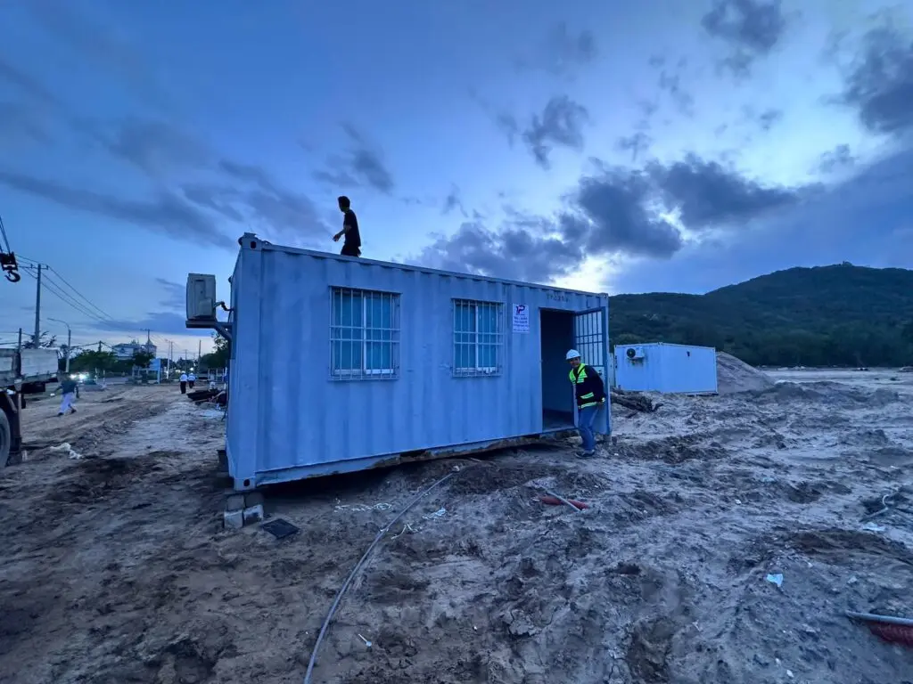 Container văn phòng 20ft sơn xanh nhạt cửa sổ khung bảo vệ trên nền cát, núi phía sau tại Bà Rịa Vũng Tàu
