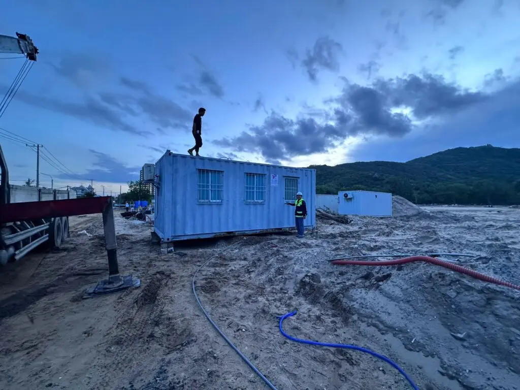 Container văn phòng 20ft sơn xanh nhạt đang được cẩu hạ lúc chiều muộn trên nền cát tại Bà Rịa Vũng Tàu