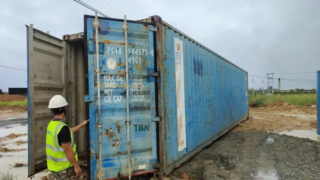 Hai công nhân kiểm tra container kho 40ft sơn xanh cũ tại Tây Ninh