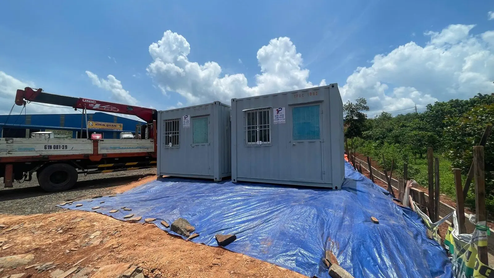 Hai container văn phòng xám đặt trên bạt xanh cạnh xe cẩu tại mặt bằng đất đỏ Bình Phước