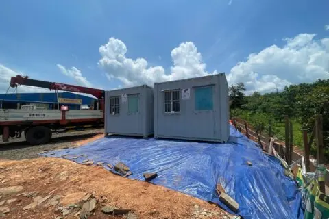 Hai container văn phòng xám đặt trên bạt xanh cạnh xe cẩu tại mặt bằng đất đỏ Bình Phước