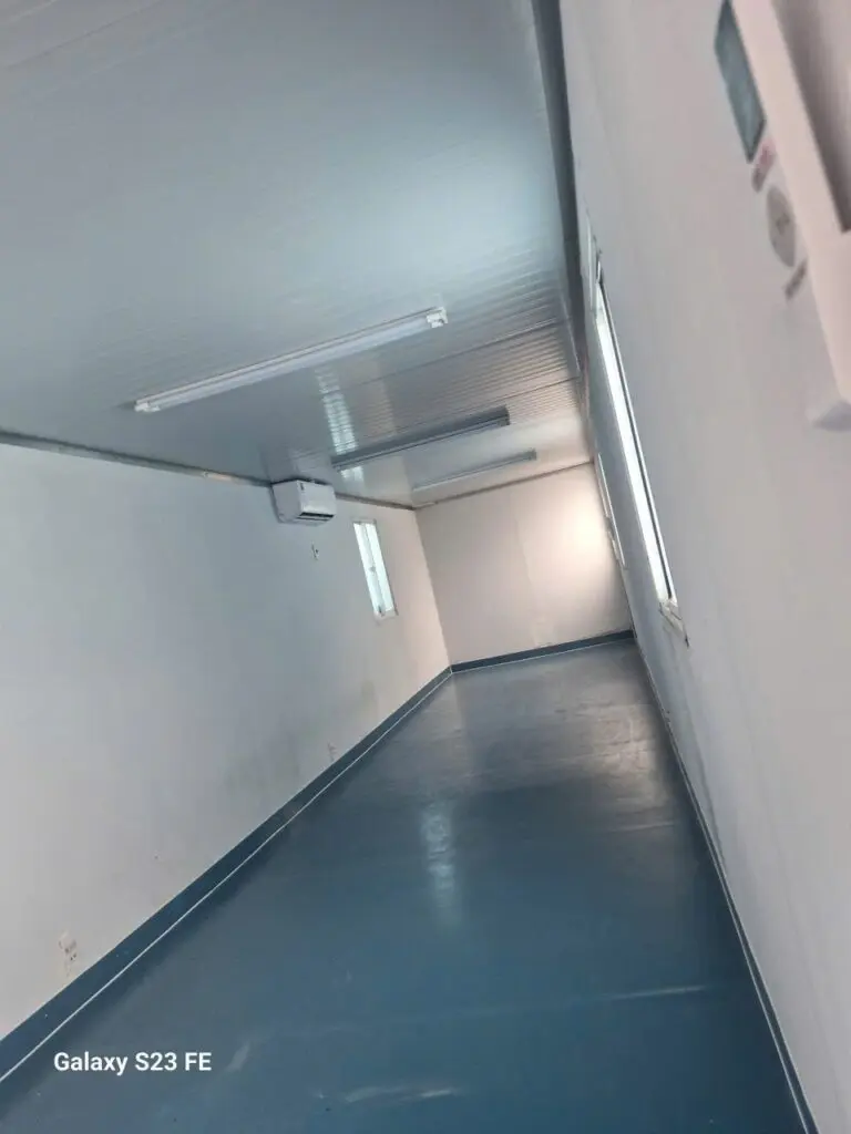 Lối đi bên trong container văn phòng 40ft có WC, sàn xanh và vách panel trắng tại cảng Long Bình