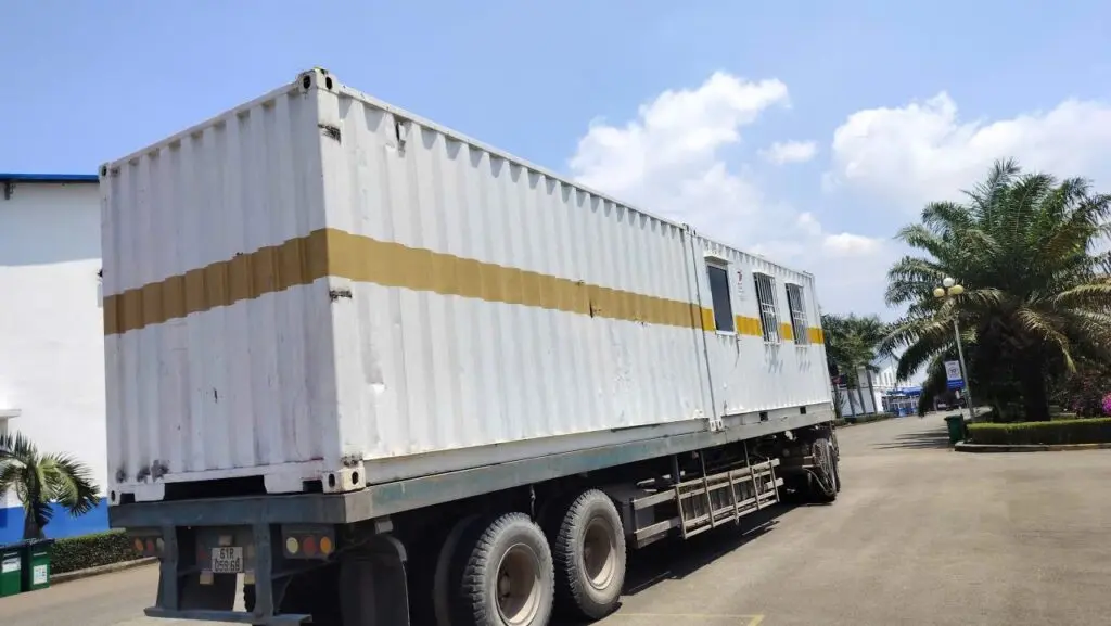 Rơ-moóc chở container văn phòng sơn trắng vạch vàng vào nhà máy KCN Đất Đỏ