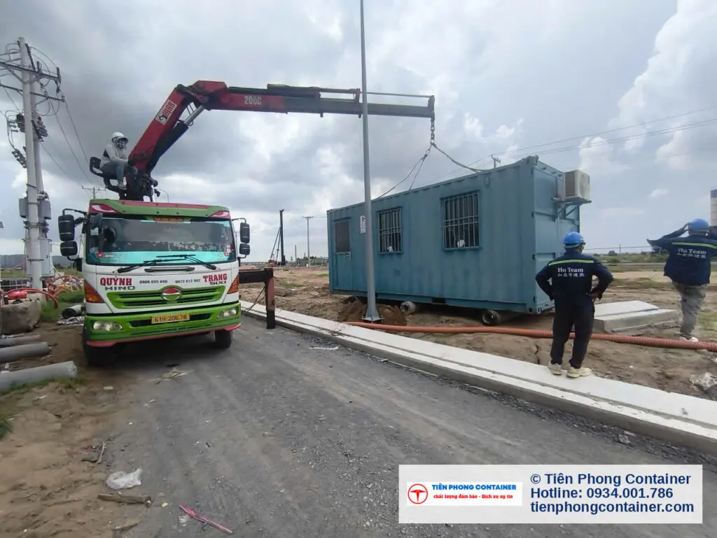 Xe cẩu hạ container văn phòng xanh ngọc cạnh đường bê tông nội bộ Aqua City