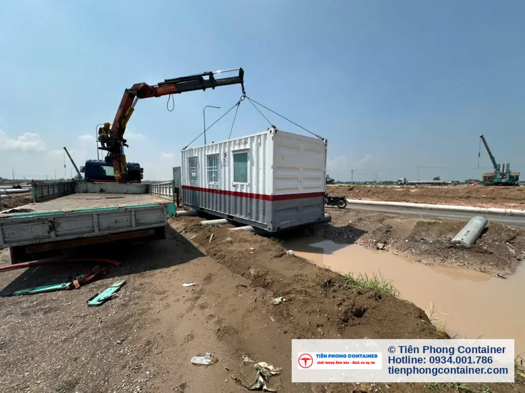 Xe cẩu nâng container văn phòng sọc đỏ trắng trên nền đất ướt tại Aqua City