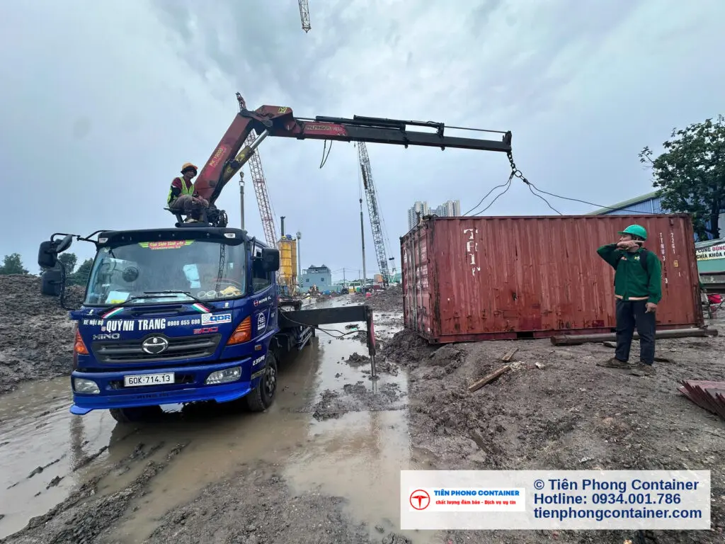 Xe cẩu và container kho 20ft đặt trên nền đất công trình, công nhân chỉ huy tại Thuận An