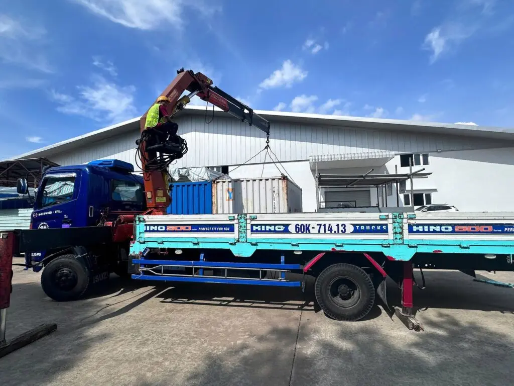 Xe tải gắn cẩu đang cẩu container kho 20ft trong sân nhà máy tại Biên Hòa