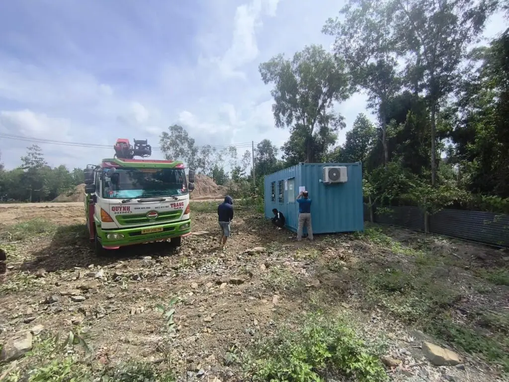Xe tải gắn cẩu đứng cạnh container văn phòng sơn xanh tại Thạnh Lợi