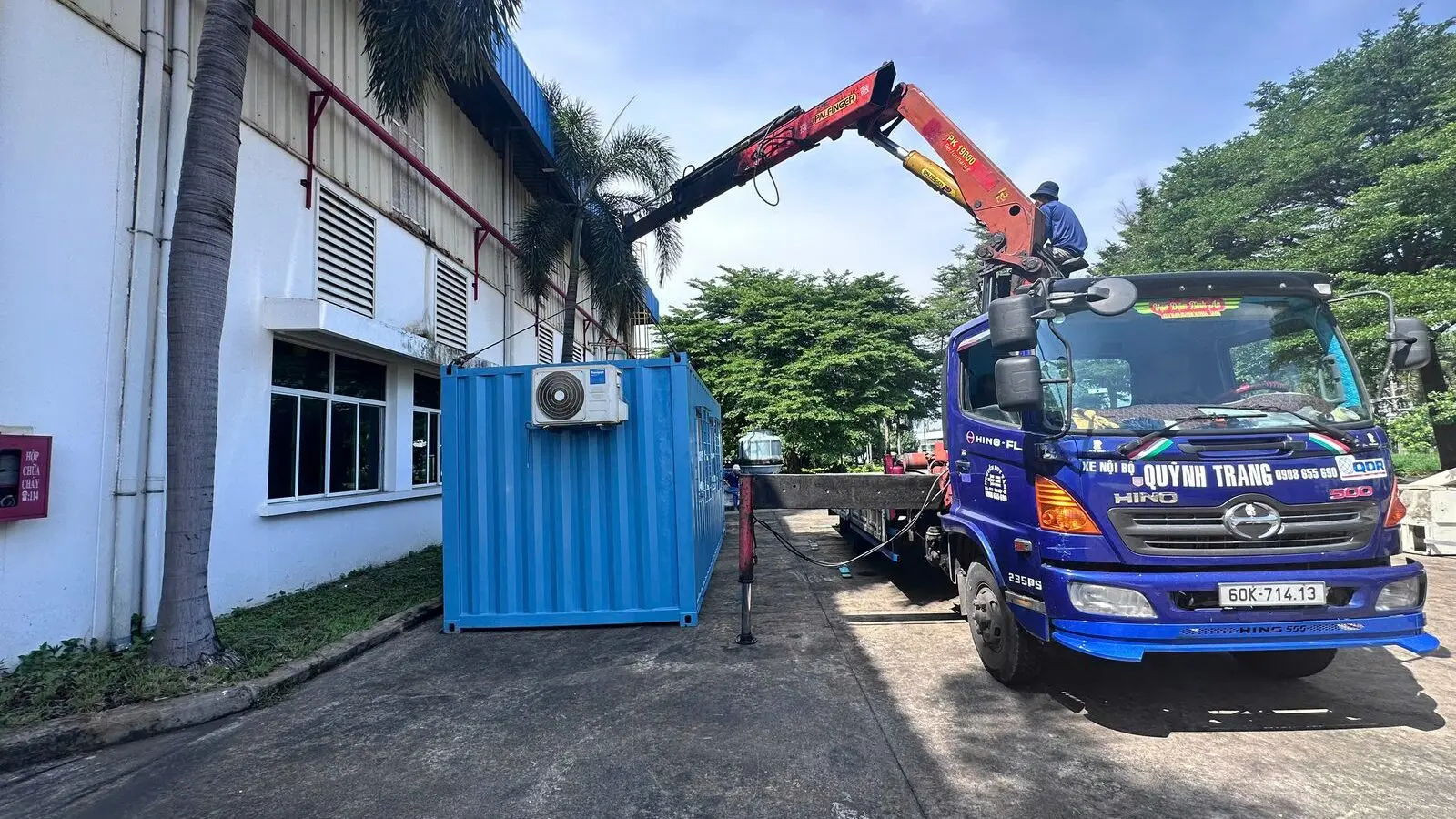 Xe tải gắn cẩu hạ container văn phòng xanh dương cạnh nhà xưởng tại KCN Long Thành