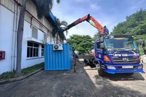 Xe tải gắn cẩu hạ container văn phòng xanh dương cạnh nhà xưởng tại KCN Long Thành